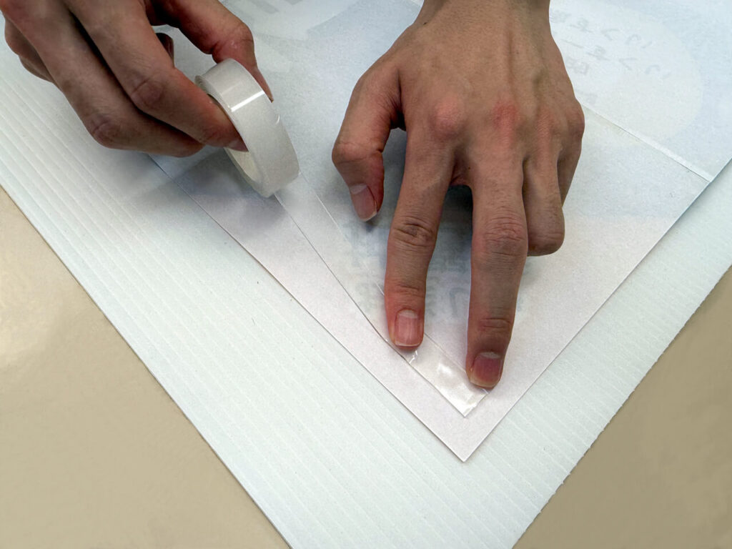 ポスターの裏側に屋外掲示用の両面テープを貼り付け
